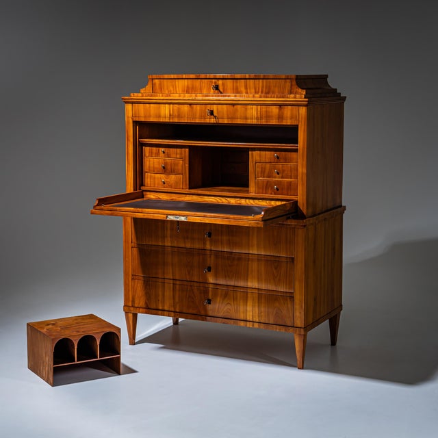 Biedermeier secretary desk raised on tapered square legs, featuring a three-drawer commode base and a flat fall-front...