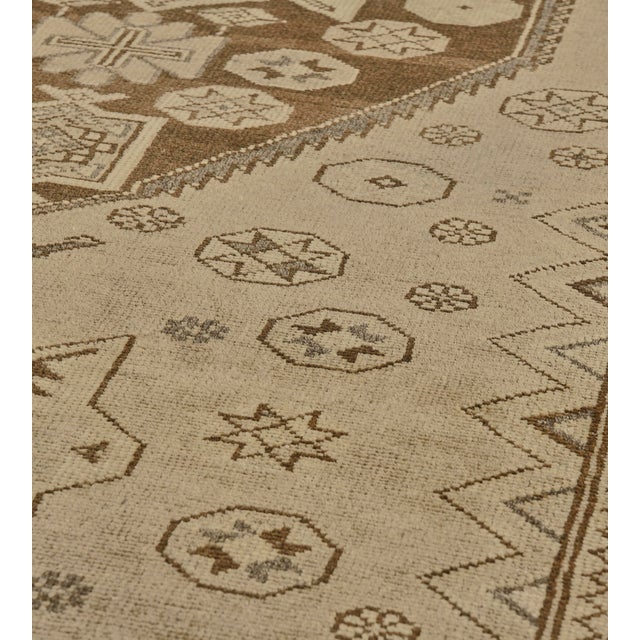 This vintage, circa 1920, Malayer runner has a buff-brown field scattered with a variety of flowerheads and stellar...