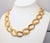 1992 goldtone textured and smooth link necklace with fold over clasp. Marked "Napier" in script with the utility patent...