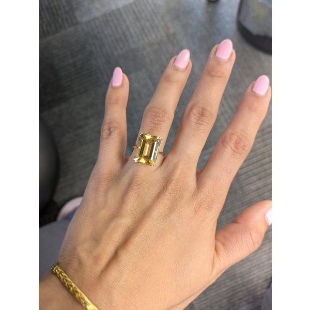A dramatic 11.78-carat citrine glows in warm golden-yellow at the center of this solid 14K yellow gold statement ring, cut...
