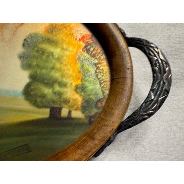 Art Nouveau oval serving tray with reverse-painted landscape scene and ornate Art Nouveau/Art Deco metal handles. The tray...