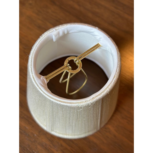 Small ivory string shade with candle clip. Top: 3" across Bottom: 5" across 4.25" top to bottom Never used