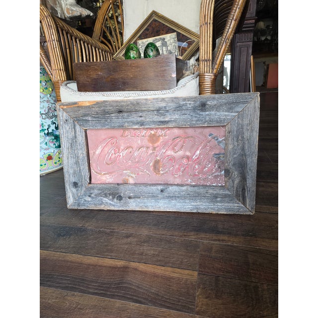 Raised metal drink Coca-Cola sign fragment mounted in a distressed barn wood frame