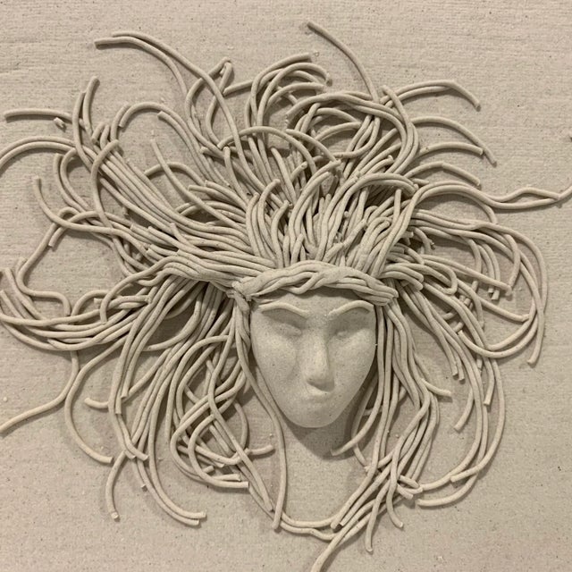 This amazing little pottery wall plaque/ sculpture is in natural clay tone and depicts a beautiful face and elaborate hair...