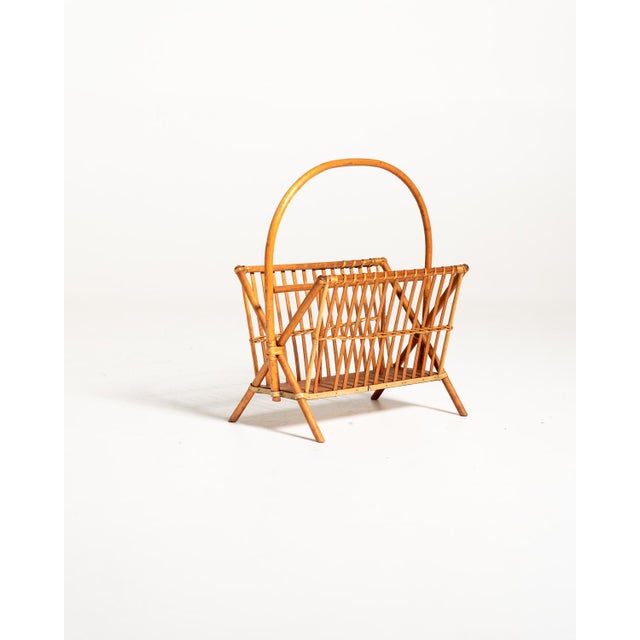 Scandinavian magazine rack from the 1960s, featuring a lightweight bamboo and rattan frame and a wide, curved handle that...