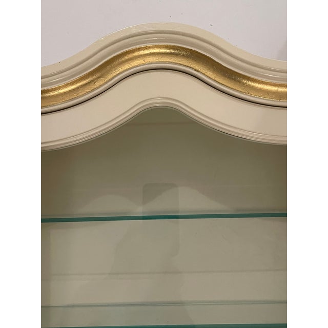 Elegant vintage Hollywood Regency antique white vitrine with gold accent and glass shelves.