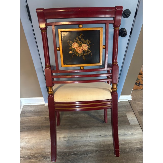 Finished in a rich lacquered red with hand-painted gold detailing, this vintage Chinoiserie-style armchair features a...