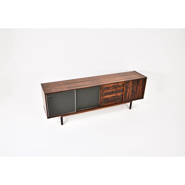 Sideboard with 2 sliding doors with skai containing a shelf, 4 drawers and a door containing a shelf. Designed by George...