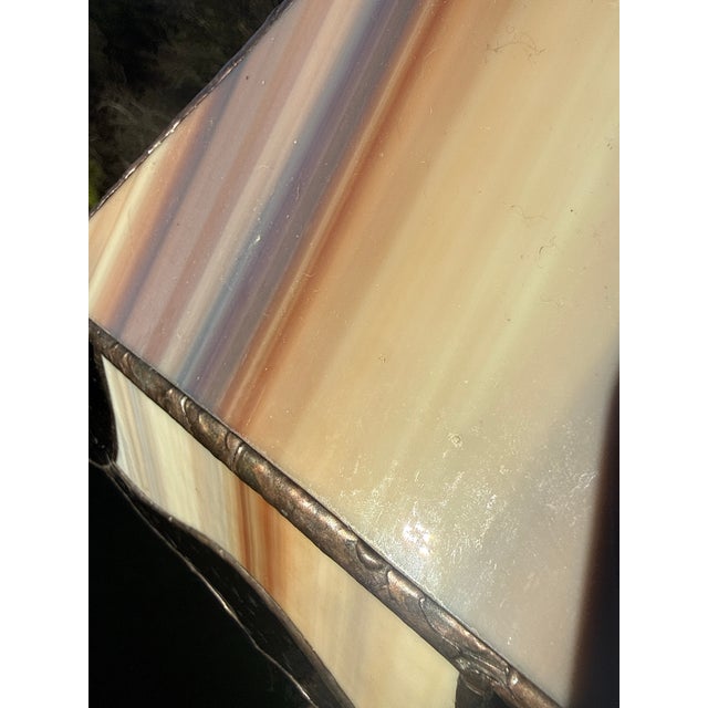 A genuine early 20th-century Arts & Crafts table lamp featuring a hand-leaded slag glass shade in warm cream, amber, and...