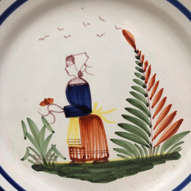 A French large faience plate with a farmer in the costume with flowers signed Henriot Quimper, circa 1950. Colorful yellow...