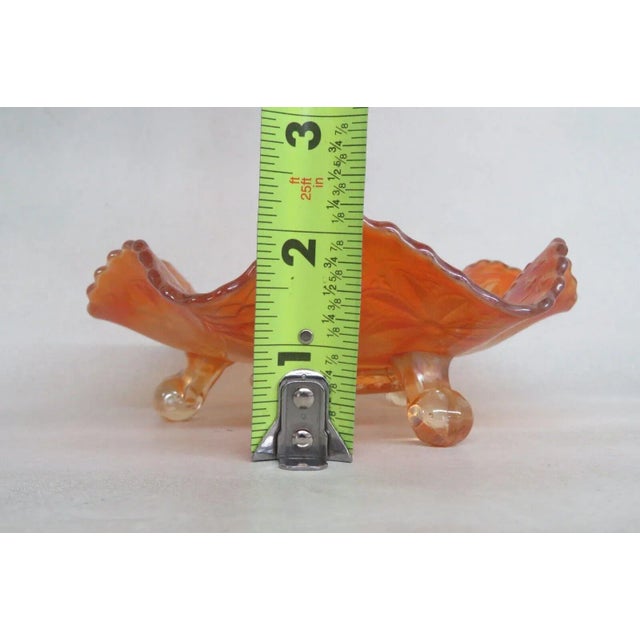 This magnificent footed dish is made of carnival glass. This dish has a lovely ruffled rim silhouette, three feet, and it...