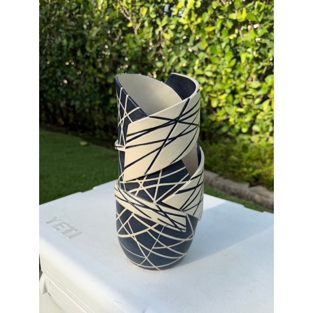 A striking contemporary studio pottery vessel featuring a bold sculptural ribbon form with an architectural black-and-...