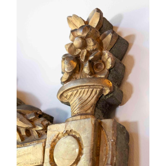 Elegant Louis XVI period mirror crafted in carved giltwood with a painted wood pediment, richly decorated with a covered...