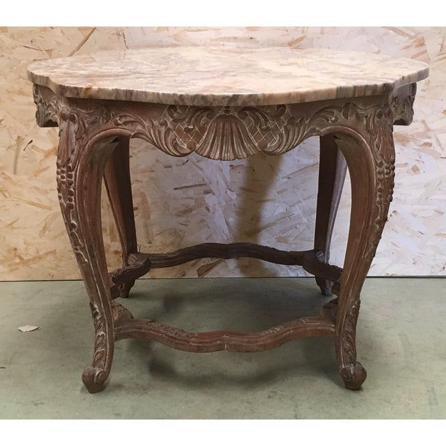 An Italian Rococo style round side table with Siena marble over a richly carved base from the 20th century. This exquisite...
