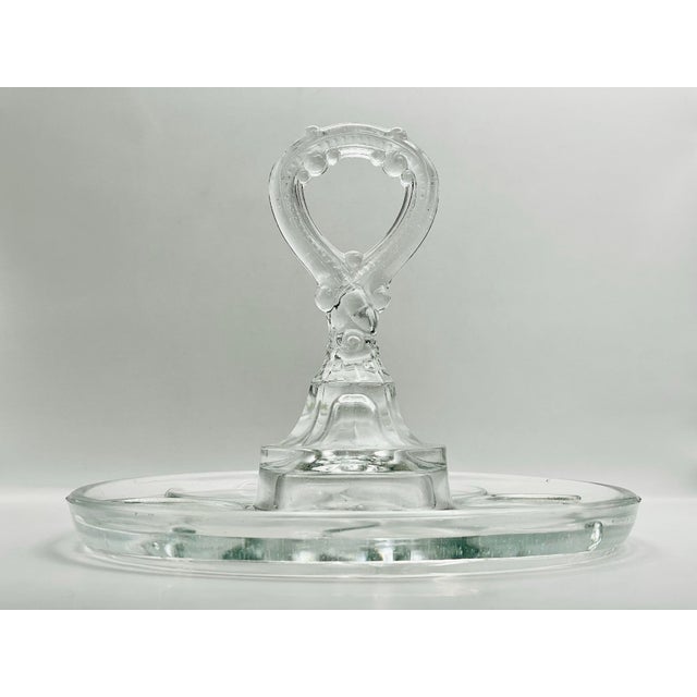 An early 20th century clear glass tray with spaces for six glasses or small bowls and a beautifully patterned handle for...