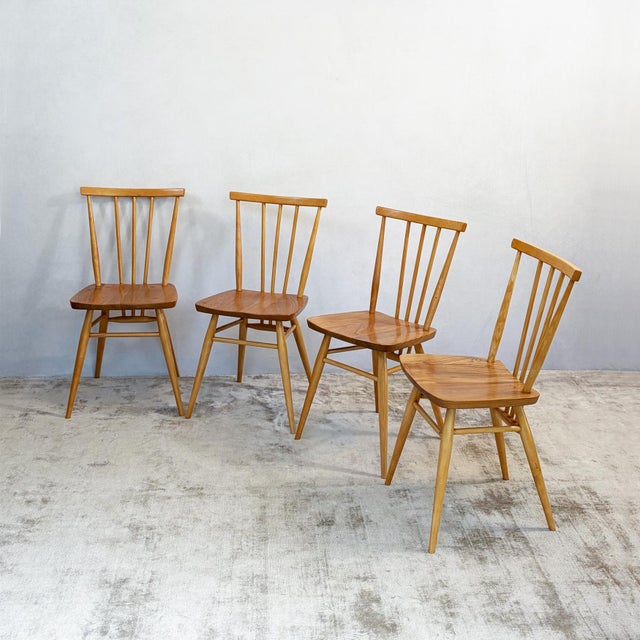 A set of four ercol 391 dining chairs, the model ercol calls the all-purpose chair. Each one has a solid elm seat with a...