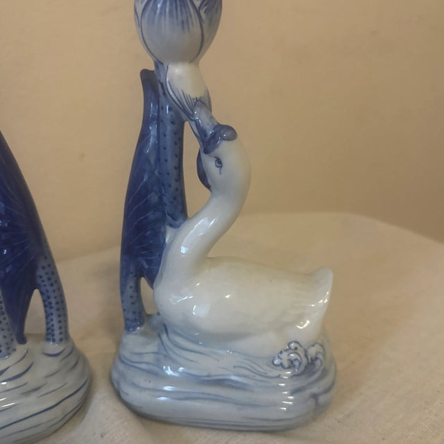 The candlesticks are made of white and blue ceramic, featuring a swan-like figure on a base of stylized waves. The swan's...