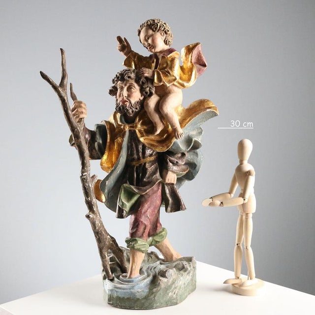 Carved, painted and gilded wooden sculpture depicting Saint Christopher and Baby Jesus crossing the river. This piece is...