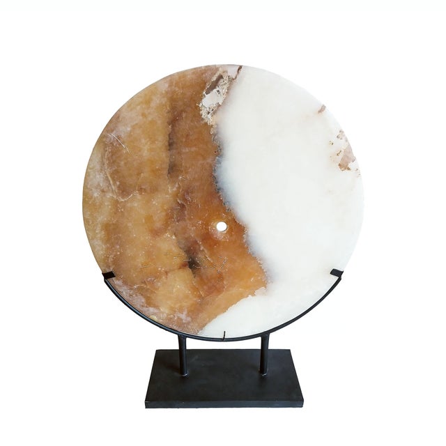 A slim Onyx stone disk, hand-carved in Indonesia, contemporary. The two-color disk was cut and polished from a transversal...