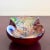 This radiant Murano-style bowl bursts with color and intricacy, featuring a deep ruby red base that swirls into ribbons of...