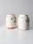 This charming set of two vintage stoneware cookie jars dates to the 1930s–1940s. Each white stoneware jar features hand-...
