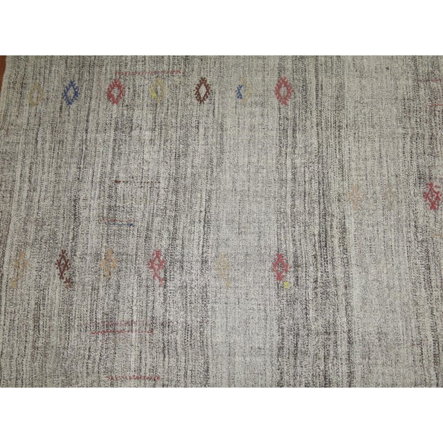 Midcentury Kilim with an abrashed gray/silver ground with small nomadic geometric motifs in earth accents. Measures: 7'1"...