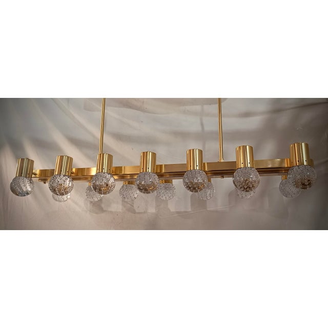 Murano chandelier with an elongated design with a brass structure and single transparent pulegoso glass. Elegant and...