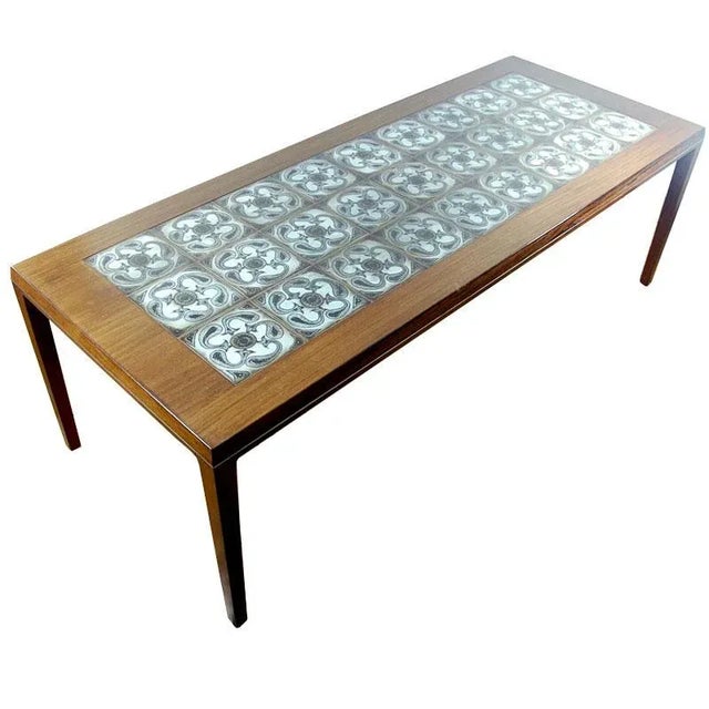 The tabletop is decorated with ceramic tiles designed by Nils Thorsson for Royal Copenhagen and a delicate aluminum strip....