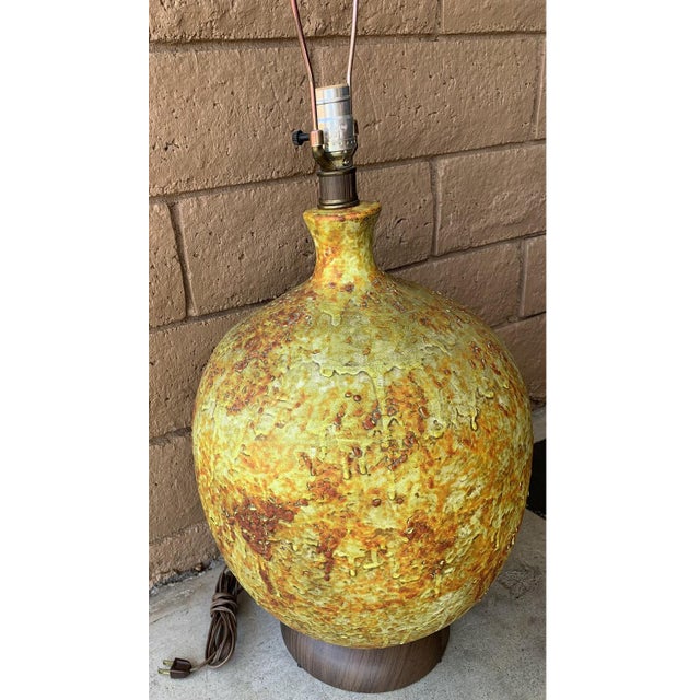 Mid century modern large pottery lamp. Rounded ceramic with abstract green orange and brink textured paint. Wooden base....