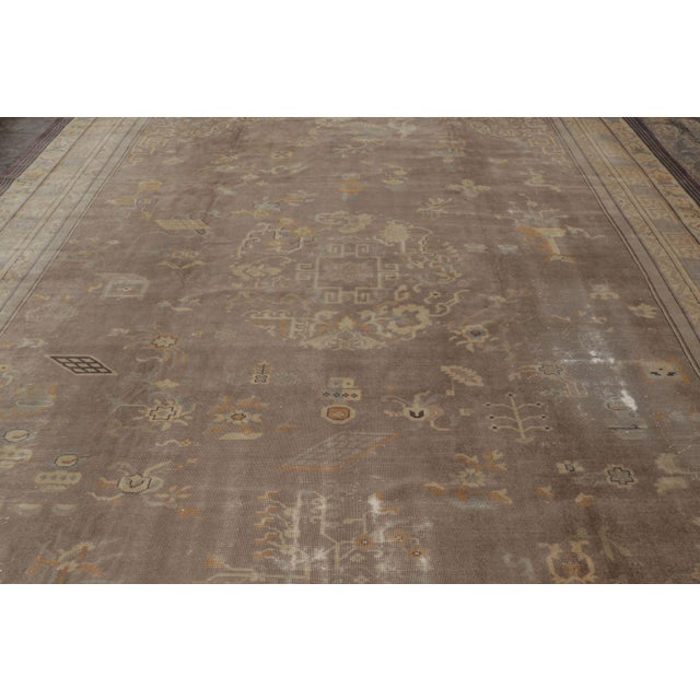 Hand-knotted in wool and originating circa 1920-1929 from Uzbekistan, this monumental 12x16 antique Khotan Samarkand rug...