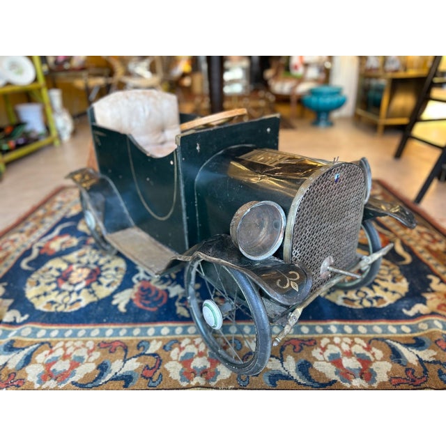 A child's car with a dark green lacquered wood and metal body, trimmed with gold piping. The body, inspired by 1920s and...