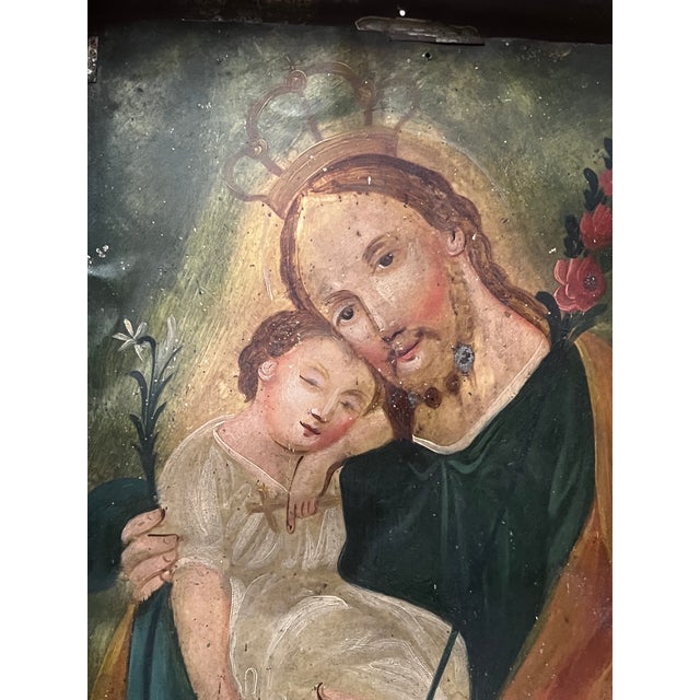 Antique Mexican religious painting on tin, known as a retablo. The painting is of Saint Joseph holding baby Jesus. Framed...
