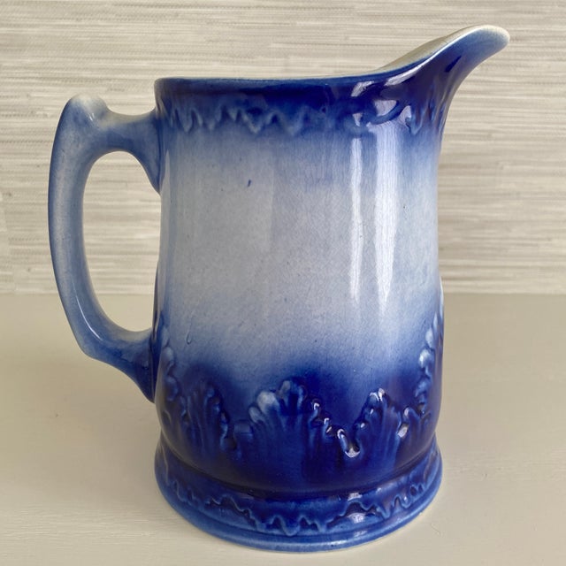 Antique Red Wing stoneware pitcher in flow blue. Heavy pitcher with wave or shell pattern around the base.