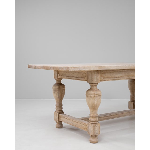 20th Century Belgian oak dining table featuring a rectangular top supported by robust baluster-turned legs joined by an...