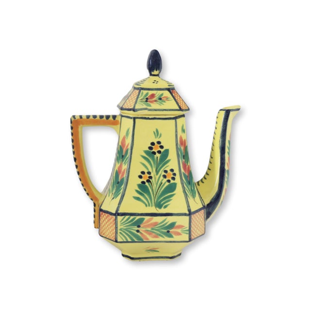 Mid 20th century French Quimper coffee pot featuring the classic hand-painted Breton figure decoration set against a warm...