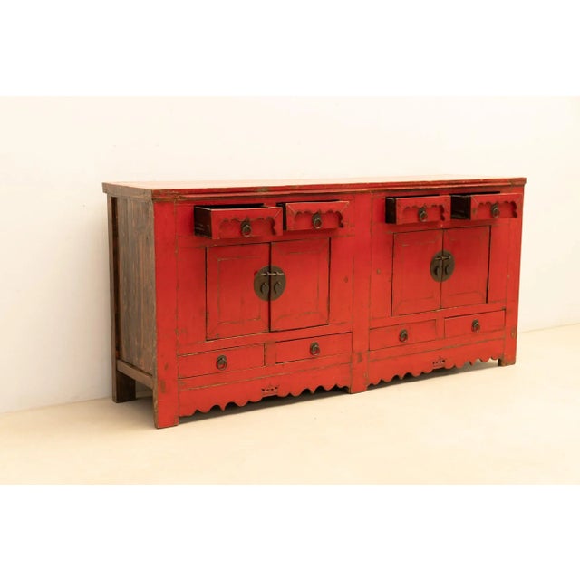 20th-century Asian decorative chest of drawers crafted from wood, adorned with a stunning red patina that adds warmth and...