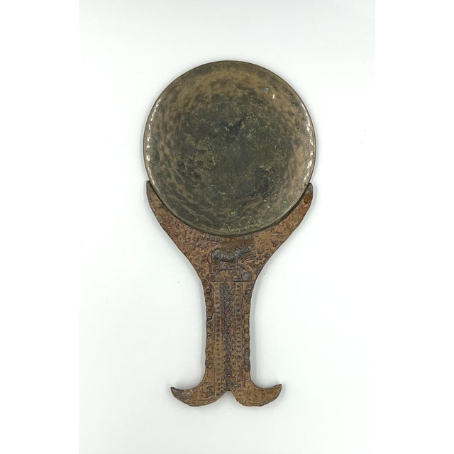 This antique, decorative bronze mirror was created by a Khmer artisan prior to the 15th century. Intricate details are...