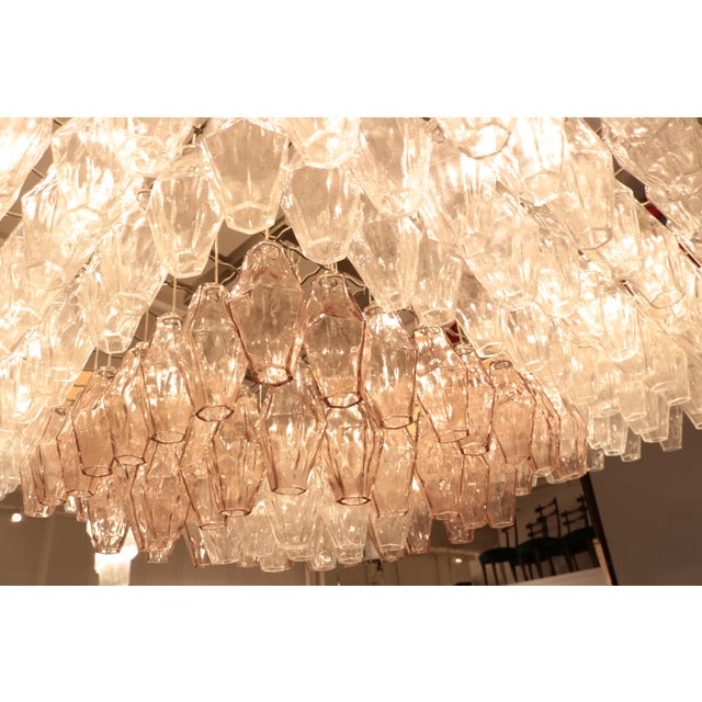 A large Venini glass light installation. Numerous clear and rose colored glass cylinders hang from a metal wire frame lit...