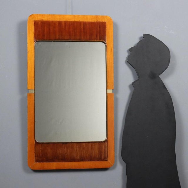 Vintage Italian-made mirror with wooden frame and brass details. This piece is attributed to the mentioned designer/maker....