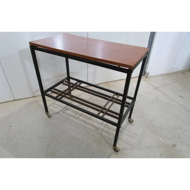 Appoint table on casters. Black metal structure, cubic. Teck and wooden crosspiece. Of the 1970s. SERVEET Signed Zuenelli.