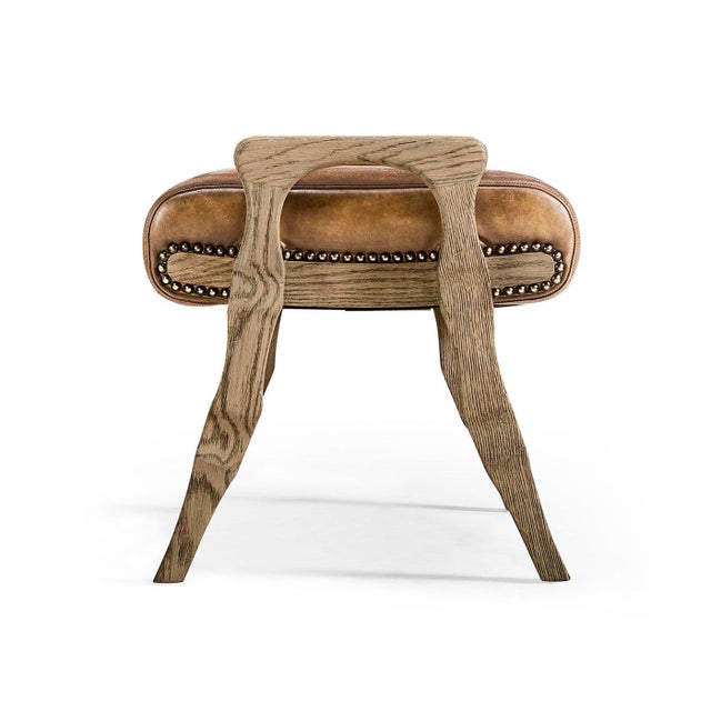 The Footstool features a thick leather seat set on sculpted, hand-carved wooden legs. The warm, distressed leather adds...