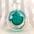 This is a green or teal green cased in clear glass round perfume bottle with two cut flat windows. The bottle is not...