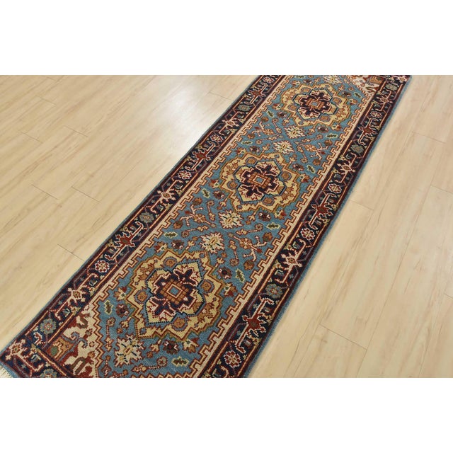 A traditional tribal Heriz runner hand-knotted with an all-wool pile on a cotton foundation. This oriental rug features a...