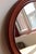 Round mirror with a molded plastic frame in a dark wood-effect finish reminiscent of mahogany, featuring attractive...
