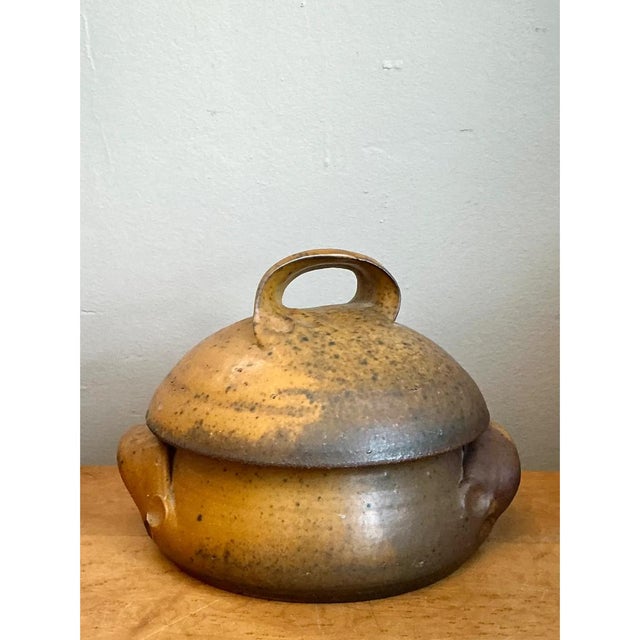 This vintage studio pottery lidded bowl is a warm, earthy piece of hand-built stoneware with a soft, pillowy silhouette....