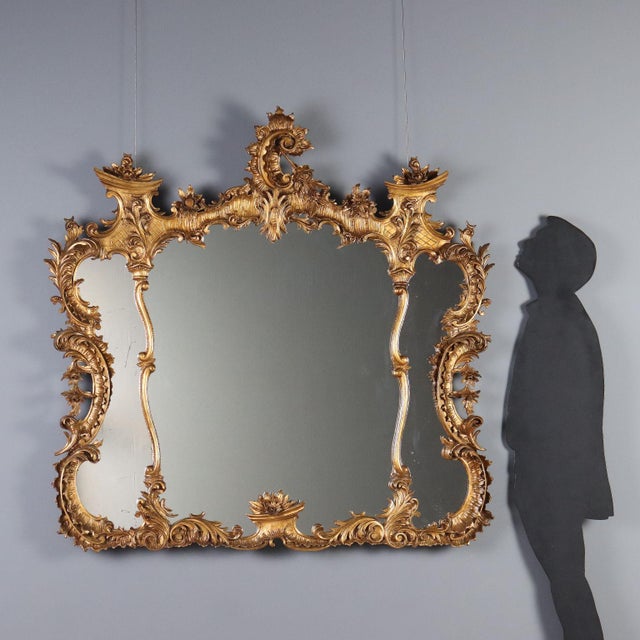 Carved and gilded wood mirror, featuring a rich and intricate design typical of the Rocaille movement. It features a...
