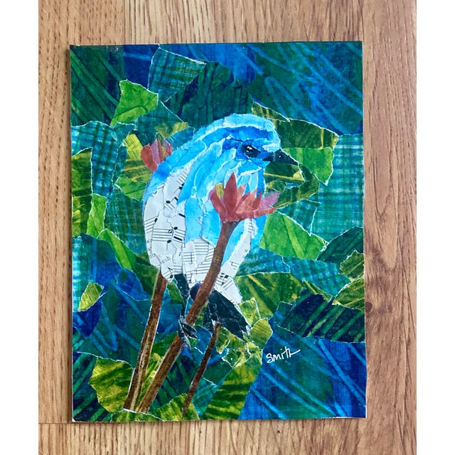 A delicate blue bird emerges from a textured mosaic of hand-torn papers in layered greens and blues, with vintage sheet...