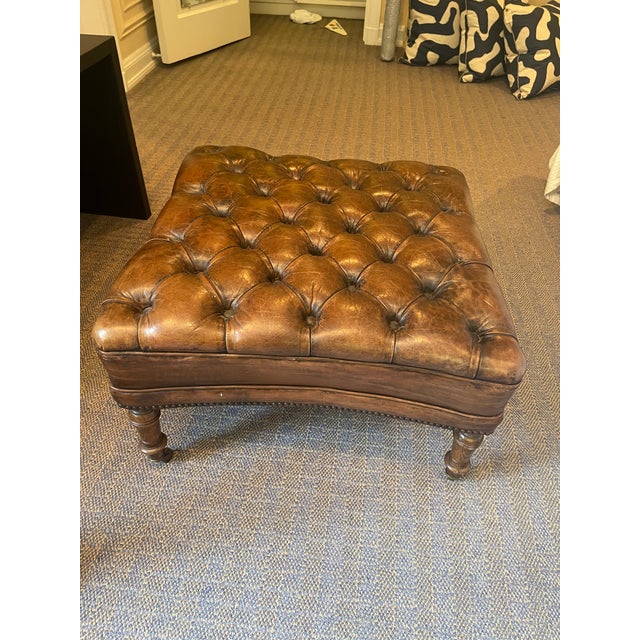 A well-proportioned, tufted leather ottoman or footstool upholstered in exquisite brown leather with deep button tufting...