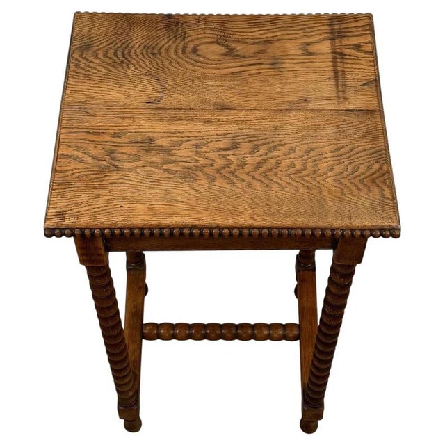 A charming early 20th-century English side table, finely crafted from oak and distinguished by its extensive bobbin-turned...