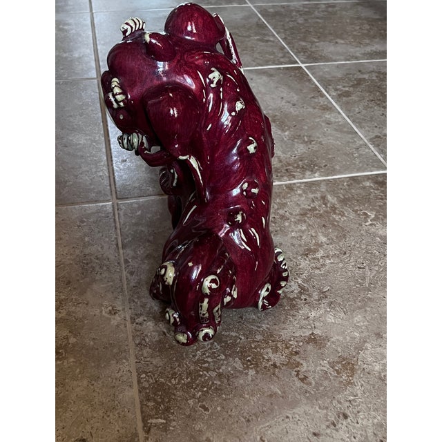 Deep, red glazed, porcelain Foo Dog with white accents. Beautifully detailed with raised tail and front feet on a ball...